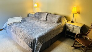 A bedroom with a bed, two bedside lamps, a chair, and a nightstand. - Gateway to Adventure! (Durango)