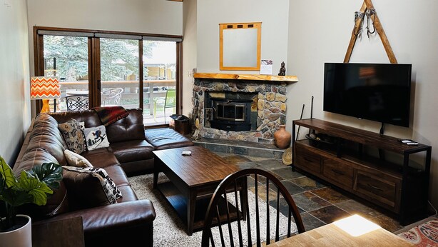 A living room with a stone fireplace, a television, a sofa, and a dining area. - Gateway to Adventure! (Durango)