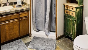 A bathroom with a shower curtain, a sink, a mirror, a green cabinet, and a toilet. - Gateway to Adventure! (Durango)