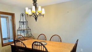 A dining room with a wooden table, six chairs, a chandelier, and a decorative metal piece on the wall. - Gateway to Adventure! (Durango)