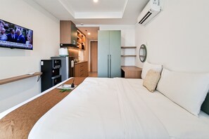 Une chambre d’hôtel comprenant un lit, un bureau, une télévision, une kitchenette et une salle de bain.