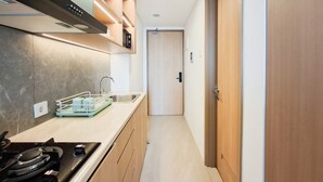 A narrow kitchen with a stove, sink, and cabinets. - Studio Minimalist Areum Residence At Antasari Place (Jakarta)