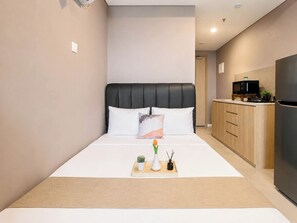Ein modernes Schlafzimmer mit Bett, Nachttisch und einer kleinen Küchenzeile.