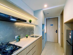 A modern kitchen with a gas stove, stainless steel sink, and a built-in oven. - Bright And Spacious Studio Apartment At Antasari Place (Jakarta)