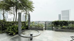 A rooftop terrace with a circular seating area, potted plants, and a view of surrounding buildings. - Bright And Spacious Studio Apartment At Antasari Place (Jakarta)