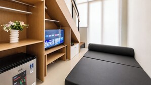 Ein modernes Zimmer mit einer Holzhochentine, einem Flachbildfernseher, der 'AVENGERS' zeigt, einer GEA Gaming-Konsole und einem grauen Sofa.