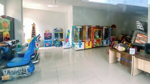 Ein Zimmer mit Spielautomaten, einem blauen Spielzeugauto und einem Getränkeautomaten.