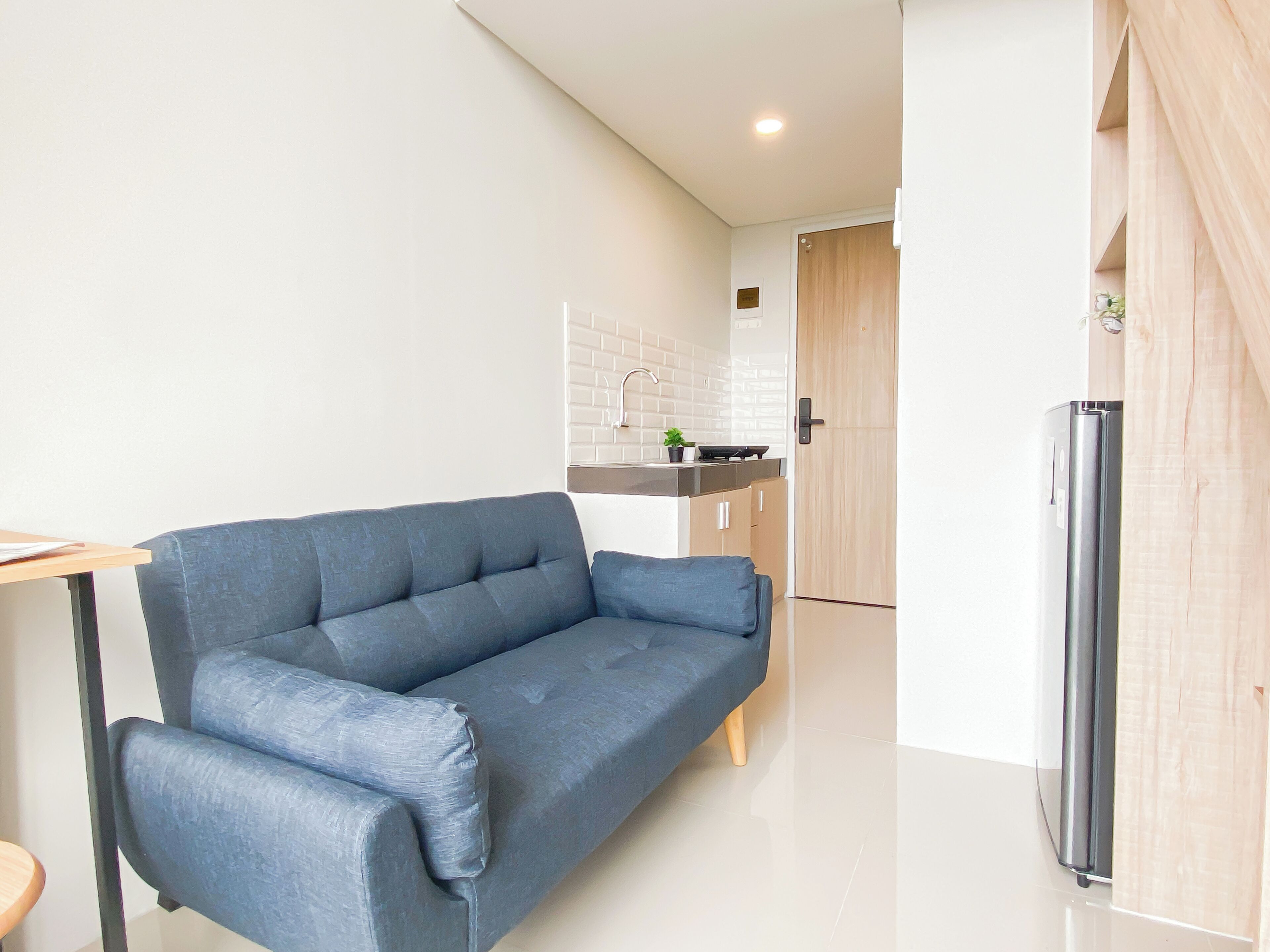 A modern living room with a sofa, a dining table, and a kitchen area in the background.