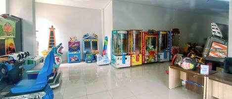 A room with arcade games, a blue scooter, and a vending machine.