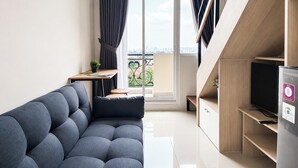 En moderne stue med en sofa, et lille bord, et fjernsyn og en balkon med udsigt over byen.