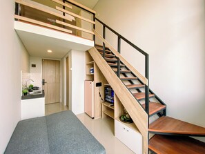 A modern interior with a staircase, a kitchen area, and a seating space. - Smart Urban Loft Studio At Apartment Apple 3 Condovilla (Jakarta)