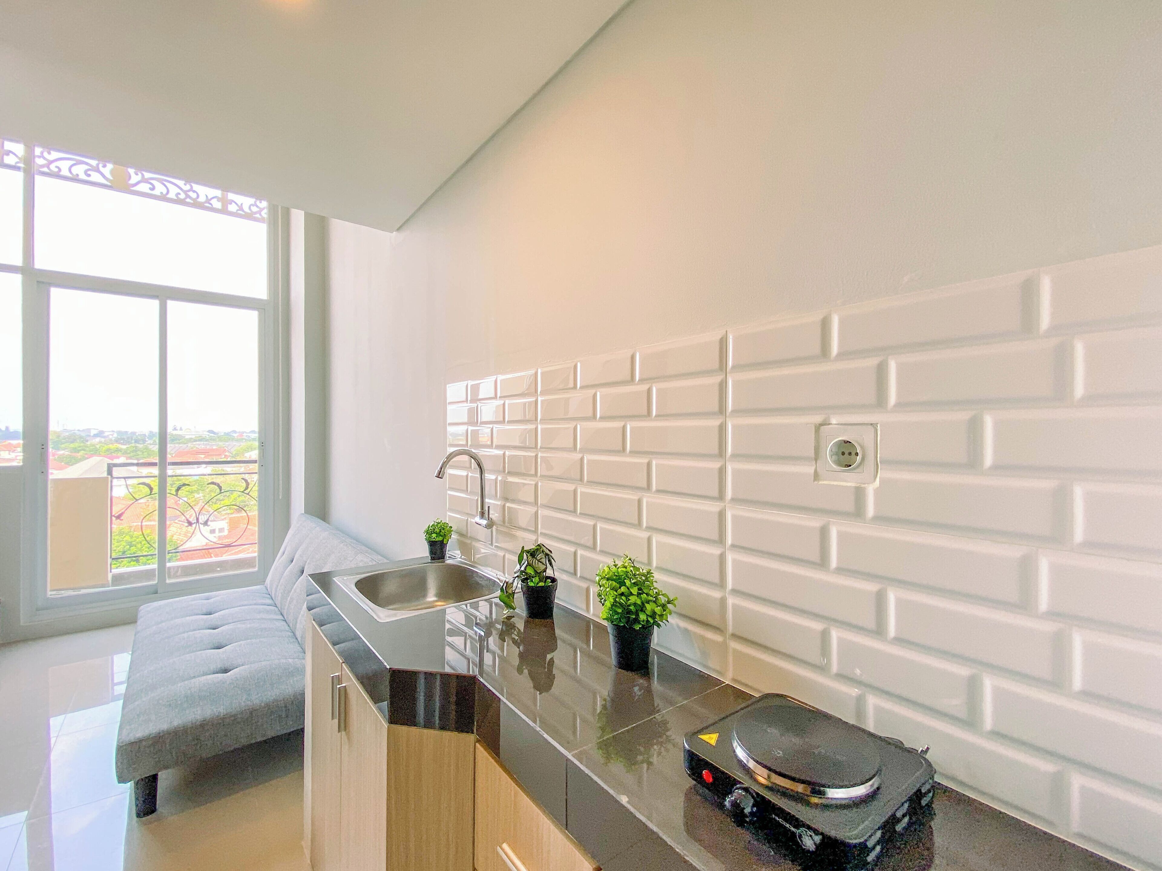 A modern kitchen with a large window, a built-in sink, and a countertop with a coffee machine.