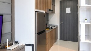 A modern kitchen with a built-in refrigerator, stove, and sink, wooden cabinets, and a grey door.