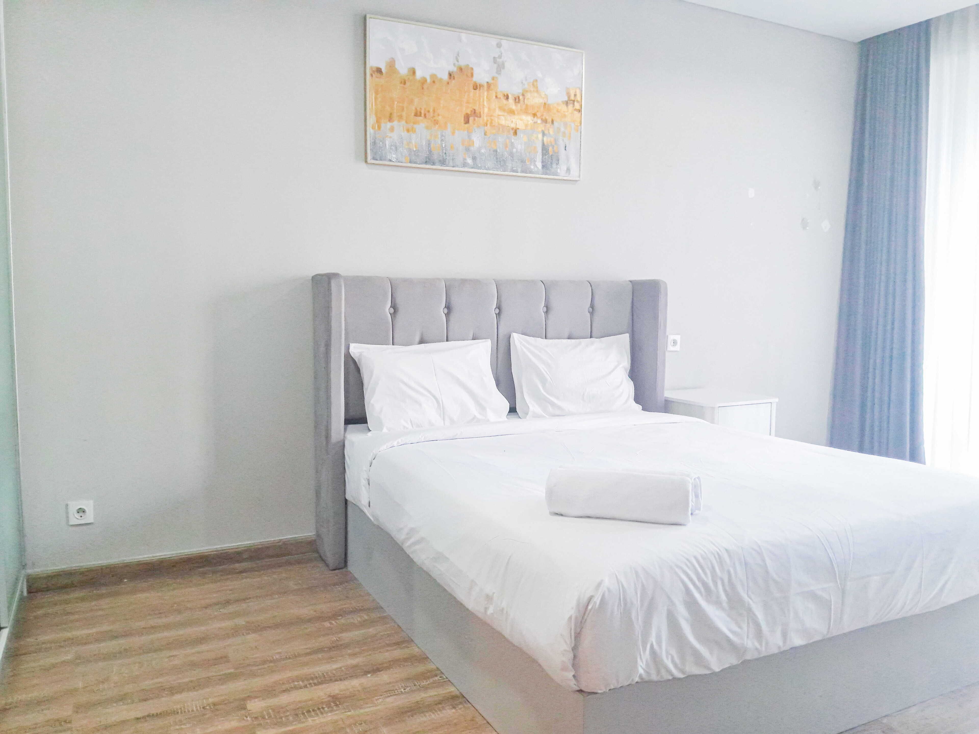 A hotel room with a bed, a nightstand, a painting on the wall, and a window with curtains.