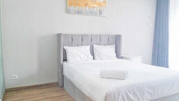 A hotel room with a bed, a nightstand, a painting on the wall, and a window with curtains.