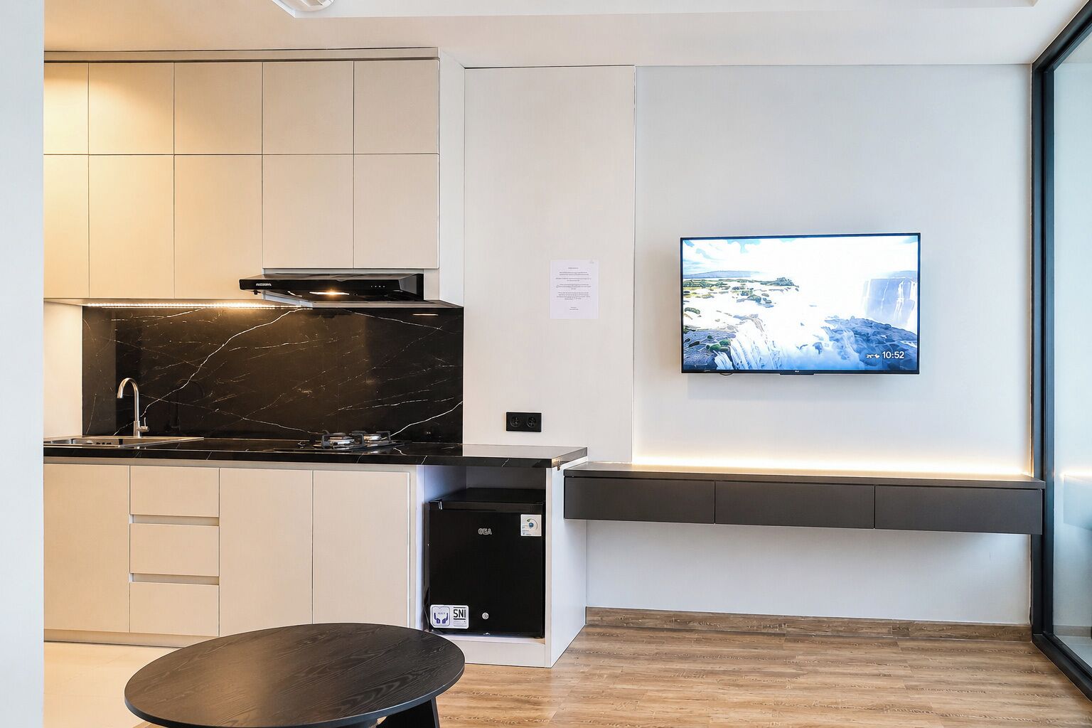 A modern kitchen with a black marble countertop, white cabinets, and a built-in oven.