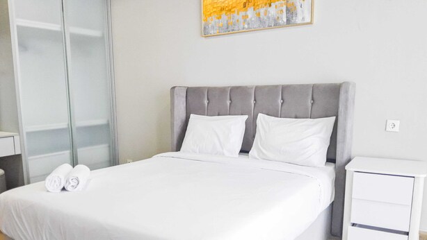 Een moderne hotelkamer met een groot bed, een nachtkastje en een schilderij aan de muur.