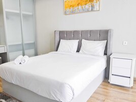 Una habitación de hotel moderna con una cama grande, una mesita de noche y un cuadro colgado en la pared.