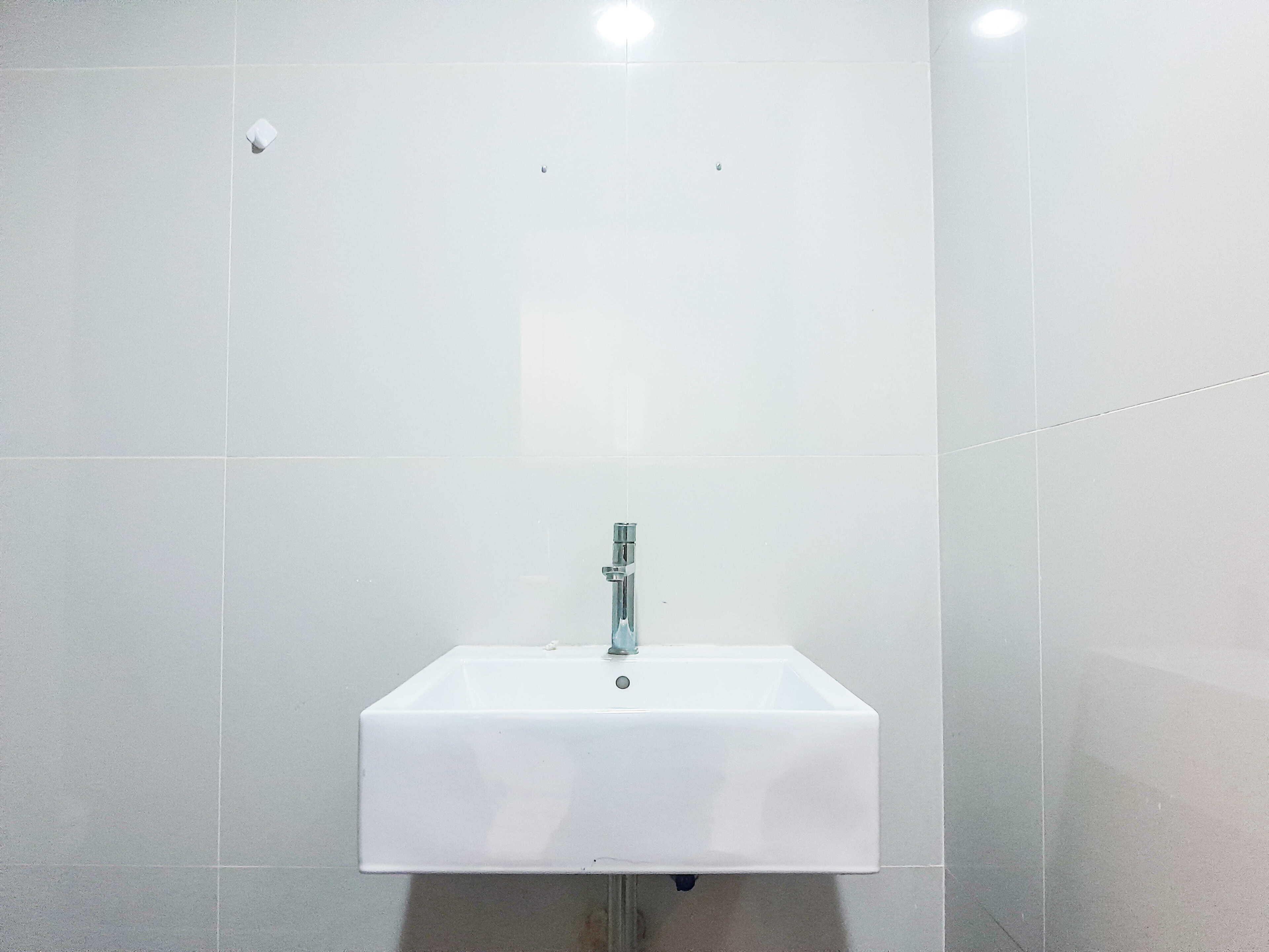 Een wit wastafelmeubel met een chromen kraan, bevestigd aan een betegelde muur.
