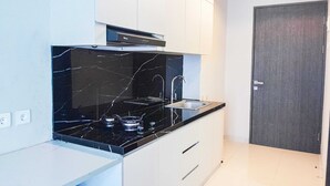 Een moderne keuken met een zwart marmeren aanrecht, een roestvrijstalen spoelbak en witte kasten.