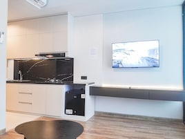 A modern kitchen with a built-in stove, a microwave, and a dishwasher. There is a flat-screen TV mounted on the wall displaying a snowy landscape.