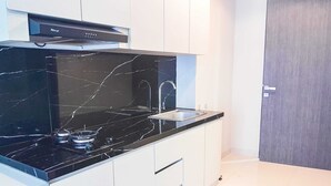 Una cocina moderna con encimera de mármol negro, pileta de acero inoxidable y muebles de cocina blancos.