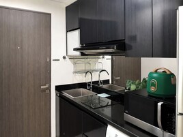 Una cocina moderna con cubierta negra, electrodomésticos de acero inoxidable y un hervidor verde.