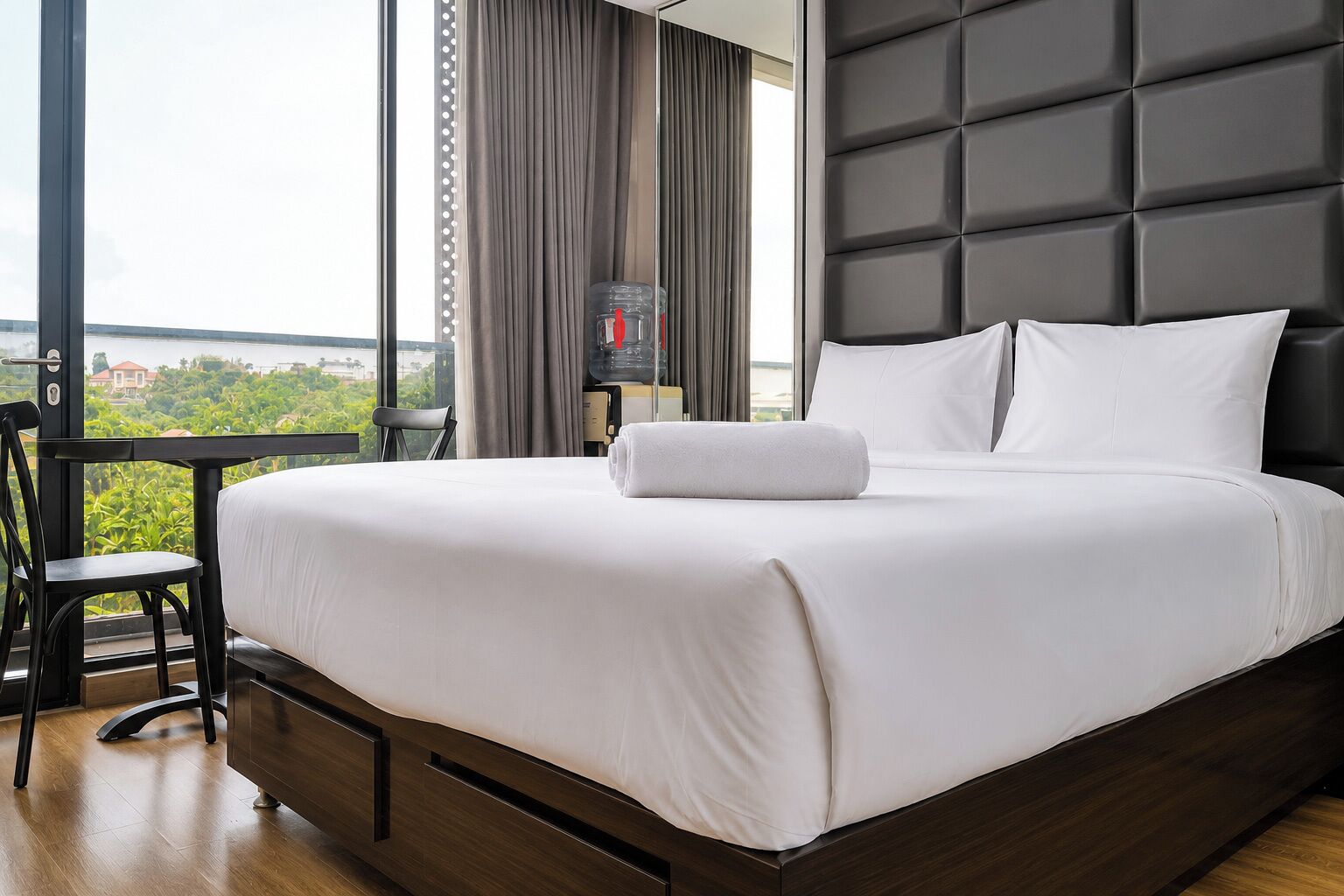 Quarto de hotel com uma cama grande, uma escrivaninha e vista para o verde.