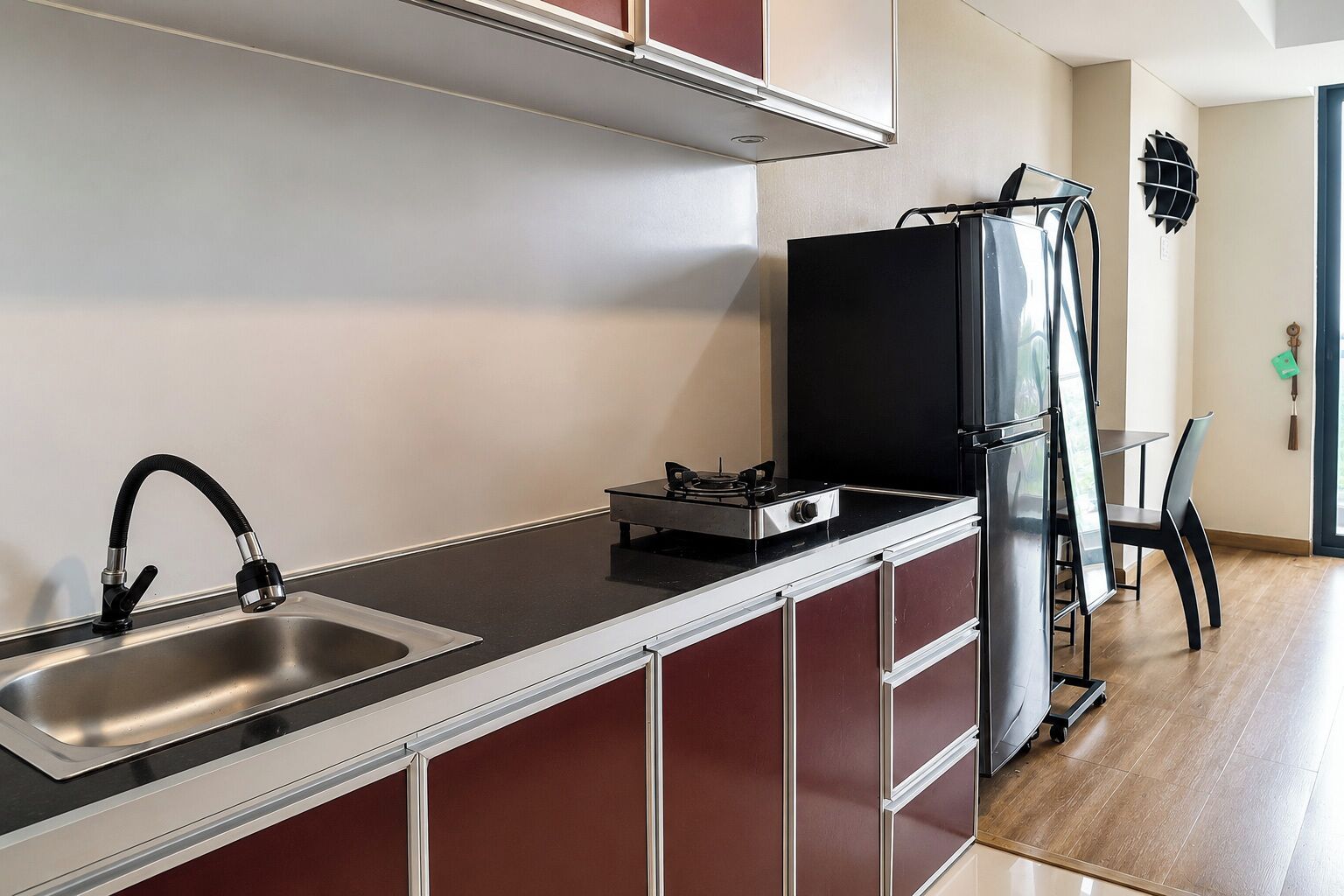 A modern kitchen with a stainless steel sink, a gas stove, and a black refrigerator.