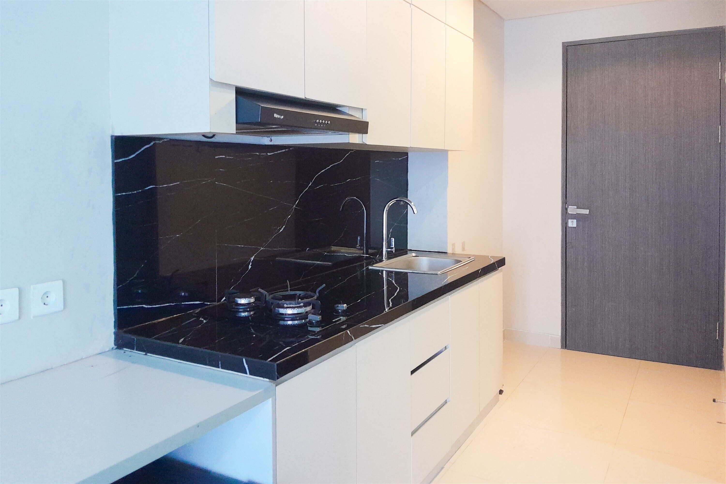 A modern kitchen with a black marble countertop, stainless steel sink, and gas stove.