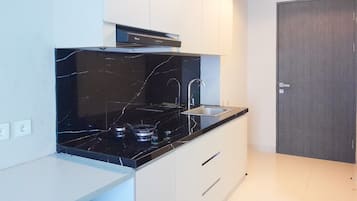 A modern kitchen with a black marble countertop, stainless steel sink, and gas stove.