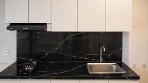 Una cocina moderna con encimeras de mármol negro, un lavamanos de acero inoxidable y una campana extractora negra.