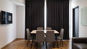 A modern room with a wooden floor, a table with chairs, and black curtains.
