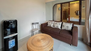 A compact living space with a sofa, a chair, a small round table, and a minibar. - 2BR Damar Pererenan Villa Near Canggu (Bali)