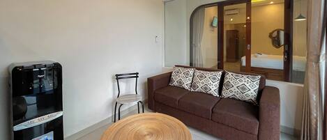 Un espacio habitable compacto con un sofá, una silla, una mesita redonda y un minibar.