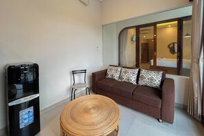 Un espace de vie compact comprenant un canapé, un fauteuil, une petite table ronde et un mini-bar.