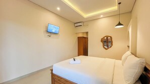 A hotel room with a bed, a television mounted on the wall, an air conditioning unit, and a mirror on the wall. - 2BR Damar Pererenan Villa Near Canggu (Bali)