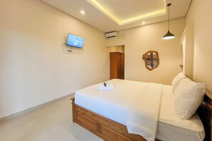 Une chambre d’hôtel équipée d’un lit, d’un téléviseur fixé au mur, d’un appareil de climatisation et d’un miroir.