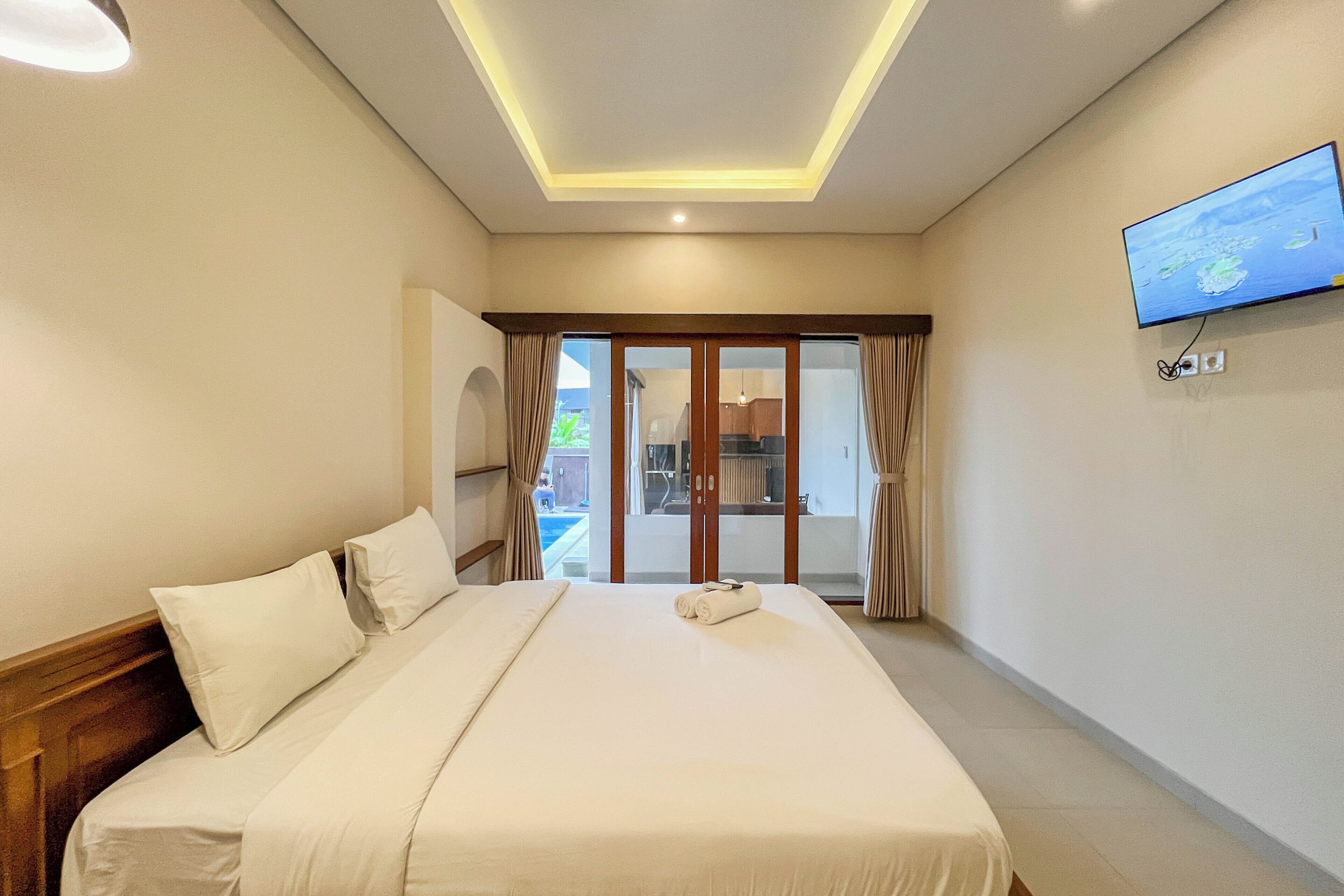 A hotel room with a bed, a television, and a view of the outside.