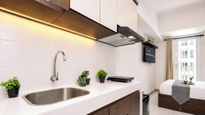 A modern kitchen with a stainless steel sink, wooden cabinets, and a built-in range hood. - Studio Polished Areum Residence At Tokyo Riverside (Jakarta)