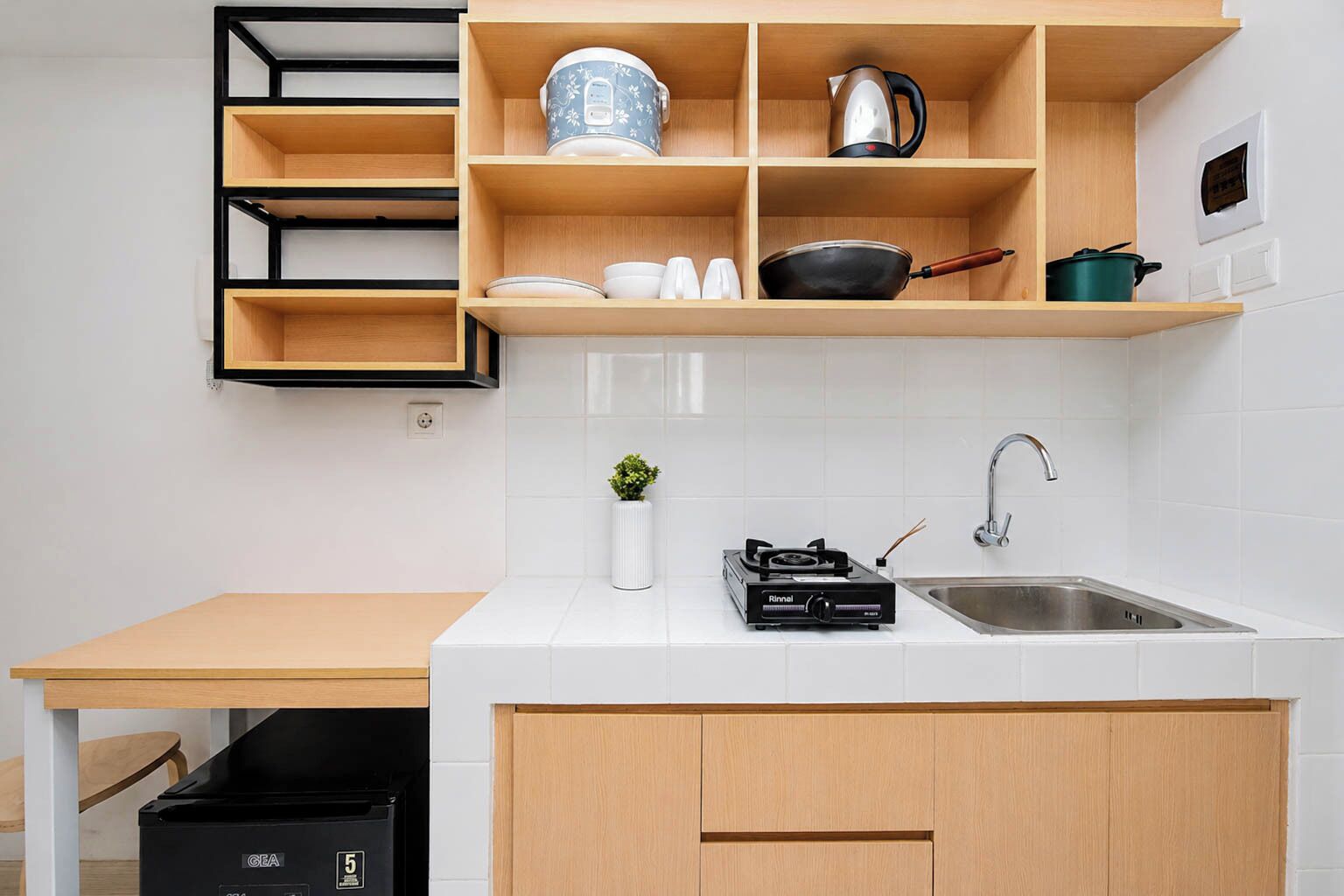 Uma cozinha moderna com bancada de madeira, uma pia embutida e uma prateleira com utensílios de cozinha.