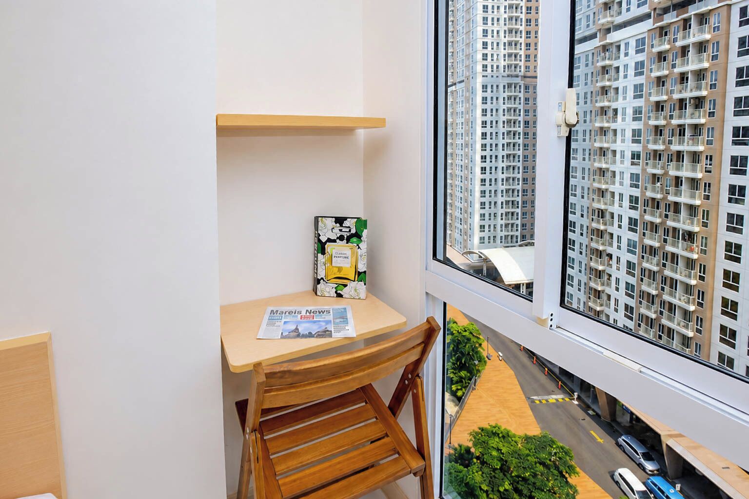 Un petit balcon avec une table en bois, une chaise, un magazine et un livre.