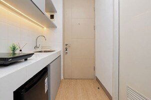 A compact kitchen with a sink, a small plant, and a wooden floor.