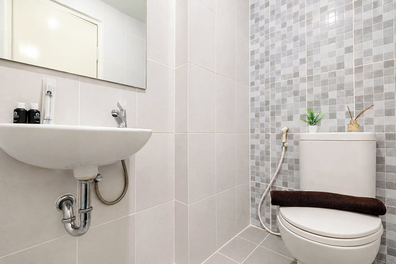 A bathroom with a white sink, mirror, and toilet.