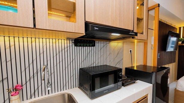 Uma cozinha moderna com micro-ondas embutido, forno Samsung e um refrigerador compacto.