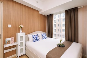 Ein Hotelzimmer mit Bett, Nachttisch, Spiegel, einem Fenster mit Vorhängen und Blick auf Gebäude.