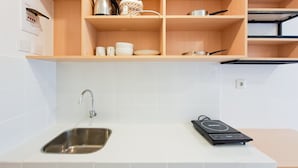 Eine Küche mit Spüle aus Edelstahl, einem Wasserkocher und einem Reiskocher auf der Arbeitsfläche.
