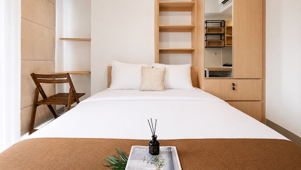 Ein Schlafzimmer mit einem Bett, einem Holzstuhl, einem Regalsystem und einem kleinen Tisch mit Tablett.