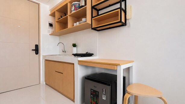 Eine kleine Küche mit einem integrierten Kühlschrank, einer Holz Arbeitsplatte und einem einzelnen Stuhl.