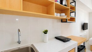Eine moderne Küche mit Spüle aus Edelstahl, Holzschränken, einer weißen Arbeitsplatte und einem kleinen Blumentopf.